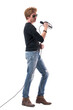 © sharplaninac - Side view of handsome young male rocker singing and holding microphone. Full body length isolated on white background.