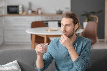 Poster - Handsome young man taking pills at home