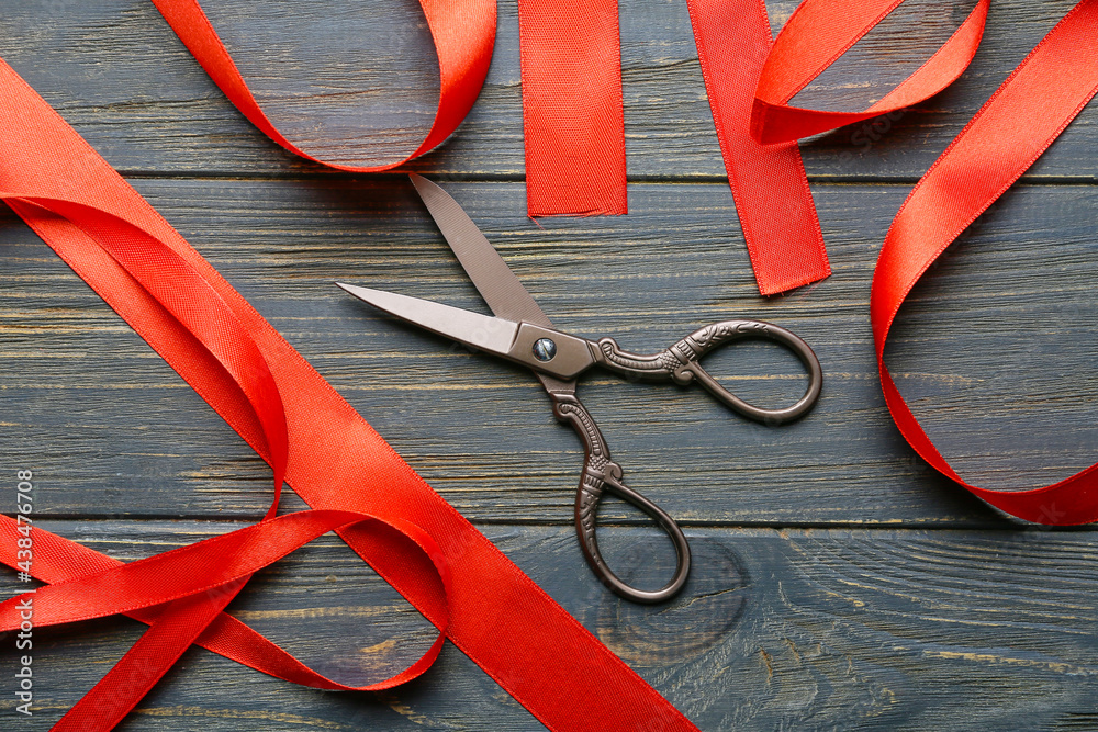Red ribbons and scissors on dark wooden background