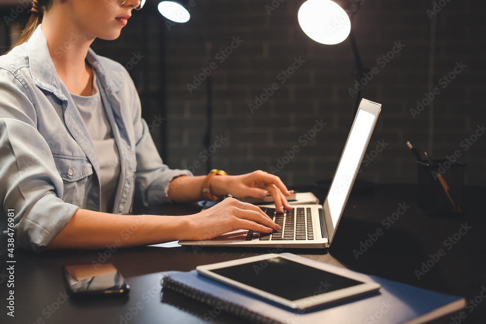 Young woman using laptop at home late in evening