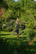 Man practicing yoga in the garden making the tree pose, Vrksasana.