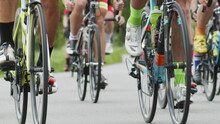 Shallow Focus Shot Of Cyclists Lower Bodies While Riding Bikes In Cycling Race. The Bicycle Wheel Is Spinning. Bicycle Wheel Rotation. Cyclist Training. Sports Healthy Lifestyle.