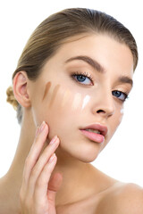 Wall Mural - Young woman applying several color samples of facial foundation cream at her face.