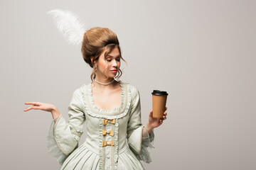 young woman in stylish vintage clothing holding takeaway drink isolated on grey