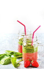 Wall Mural - Two-layered smoothies made of strawberries and spinach in a trendy jar with a handle. Next to fresh strawberries and juicy spinach leaves. organic food. For vegan and raw food nutrition. 