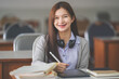 © EduLife Photos - Stock photo of a young teenage woman Asian college student in student uniform studying and writing on digital tablet in a university classroom