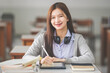 © EduLife Photos - Stock photo of a young teenage woman Asian college student in student uniform studying and writing on digital tablet in a university classroom
