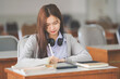 © EduLife Photos - Stock photo of a young teenage woman Asian college student in student uniform studying and writing on digital tablet in a university classroom