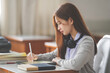 © EduLife Photos - Stock photo of a young teenage woman Asian college student in student uniform studying and writing on digital tablet in a university classroom