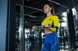 © nazarovsergey - Fit brunette doing bicep exercises on cable crossover at gym