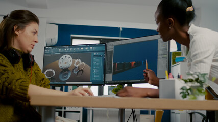 Poster - Diverse women game software developers creating game interface sitting in startup creative agency company using pc with two displays. Workers developing online video games with modern technology