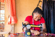 © wazkkii - african seamstress sews clothes. Workplace of tailor - sewing machine, rolls of thread, fabric, scissors.
