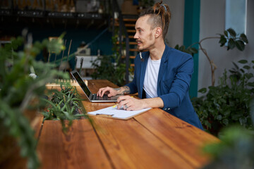 Wall Mural - Cheerful young man using laptop at work