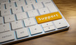 Keyboard with support key. Close up of a computer keyboard on a wooden table. One key is yellow with the word Support on it. 3D illustration.