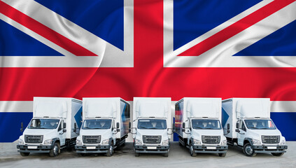 Great Britain flag in the background. Five new white trucks are parked in the parking lot. Truck, transport, freight transport. Freight and logistics concept