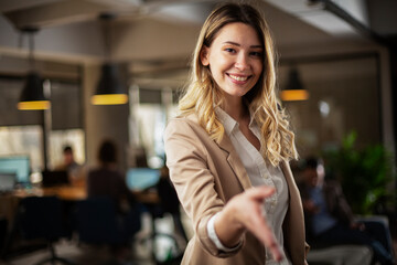 Wall Mural - Happy businesswoman in office. Portrait of beautiful businesswoman offering hand for handshake..