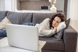© zinkevych - A woman in white sweater lying on the sofa and watching something online