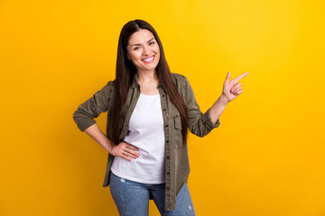 Poster - Photo of impressed charming young woman wear khaki outfit pointing finger empty space isolated yellow color background