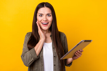 Poster - Photo of adorable impressed lady dressed dreen clothes arm cheek holding modern device isolated yellow color background