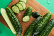 Set of fresh whole and sliced cucumbers on a wooden board with water drops. Garden cucumber wallpaper backdrop design