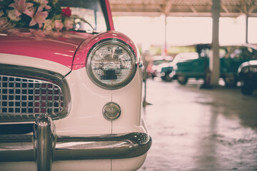 Close up round headlights of pink vintage classic car. Transportation and retro car collection concept.