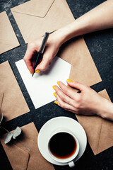 Wall Mural - Woman writes letter on black background top view and envelopes around