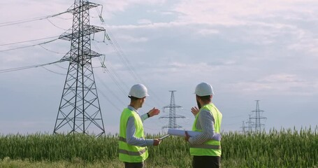 Wall Mural - two engineers discuss a blueprint for a high-voltage power line on a tablet and a paper drawing. eng