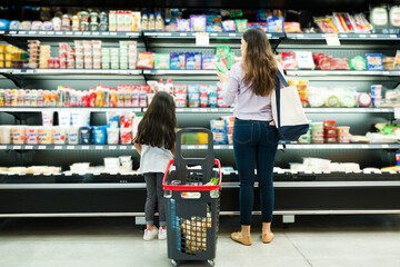 Wall Mural - Young woman and little girl deciding food brands