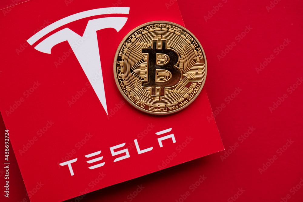 LONDON, UK - June 2021: Bitcoin cryptocurrency on a Tesla electric vehicle logo