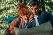 © carballo - young multiethnic young couple on a backpacking trip looking at the map