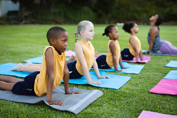 Wall Mural - Female teacher and group of diverse students performing stretching exercise in the garden at school