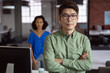 © wavebreak3 - Portrait of serious asian businessman standing in office with female colleague in background