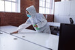 © wavebreak3 - Cleaner wearing ppe suit, glasses and mask disinfecting office workspace, wiping desks