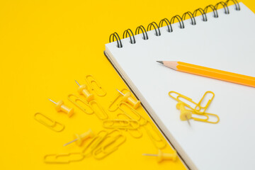 Wall Mural - Selective focus of Notebook, pencil, clip and pin on a yellow background  and copy space