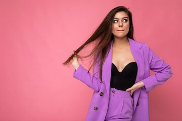 Wall Mural - Portrait of thoughtful beautiful fashionable brunette woman in casual trendy violet jacket isolated on pink background with free space