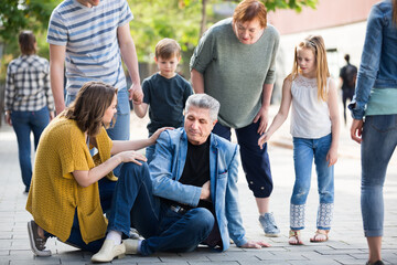  People of different ages helping mature man with pain in heart in park