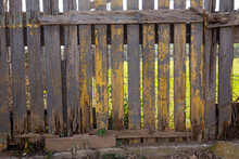 Closeup Of Old Rotten Wooden Garden Fence On Background With Green Grassland..