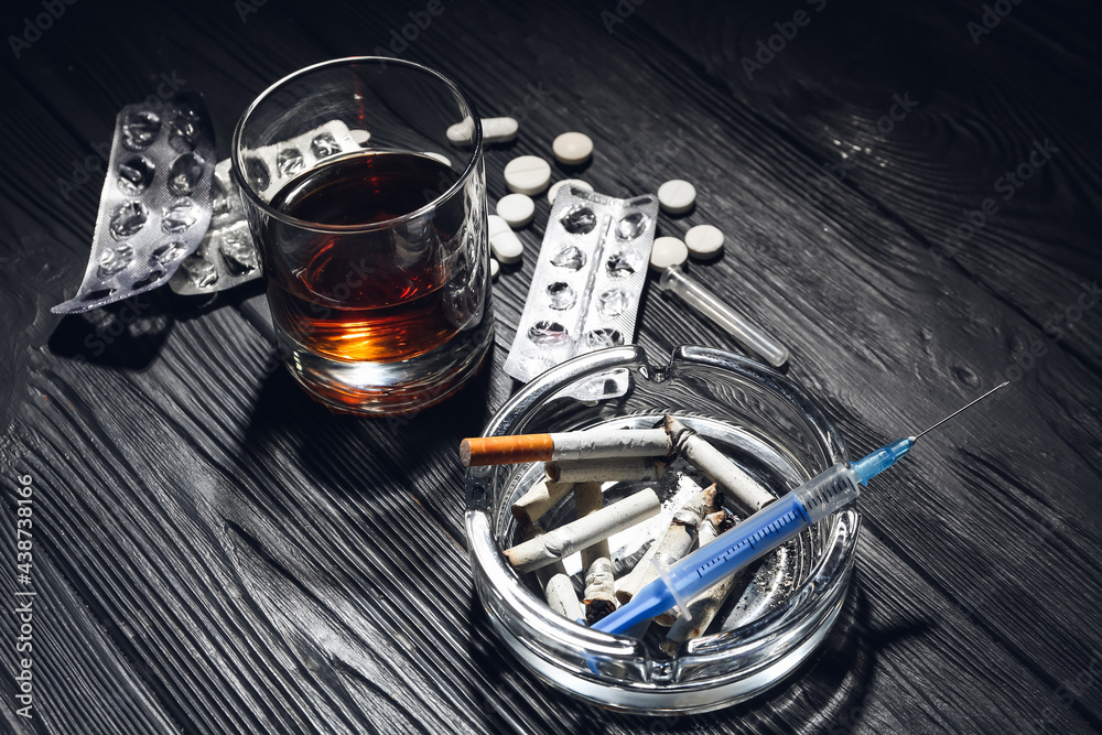 alcohol cigarettes and drugs are all examples of Alcohol, drugs and cigarettes on table. Concept of addiction Stock Photo