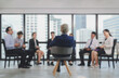 © paepae stocker  - Soft blurred business background of senior caucasian male manager leading meeting with small asian team staff at city building office space.