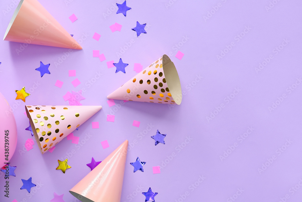 Party hats and confetti on color background