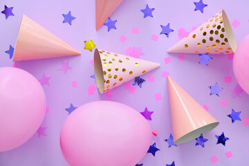 Party hats with air balloons and confetti on color background