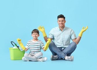 Poster - Father and son with cleaning supplies meditating on color background