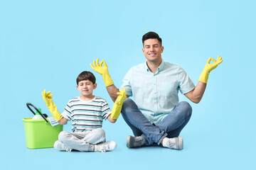 Poster - Father and son with cleaning supplies meditating on color background