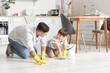 © Pixel-Shot - Father and son cleaning floor in kitchen