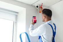 Worker with mobile phone checking alarm system indoors