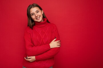 Young smiling beautiful brunette woman with sincere emotions isolated on background wall with copy space wearing casual red sweater. Positive concept