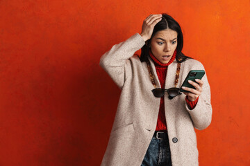 young hispanic woman expressing surprise and using mobile phone