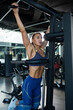 © nazarovsergey - Confident brunette doing pull ups on machine at gym