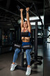 © nazarovsergey - Girl doing reverse grip high lever row on strength machine at gym