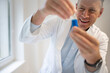 © epiximages - male chemist, scientist works at standing table and examines blue liquids in small vials and wears white coat